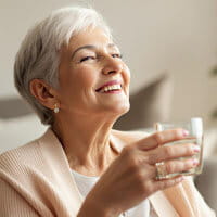 Portrait of Betty J., an American woman in her 40s with light brown hair, smiling warmly in a bright kitchen